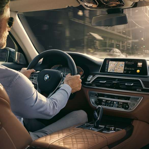 BMW 7 серии Седан: возможности подключения BMW 7 серии Седан: мужчина использует возможности подключения BMW сидя в автомобиле