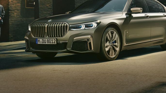 BMW M760Li xDrive в городе BMW M760Li xDrive: в движении по городским улицам, вид сзади сбоку
