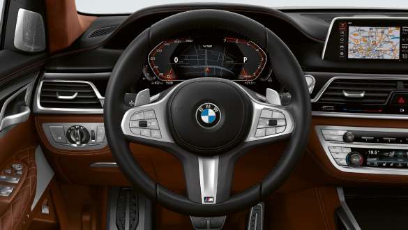 BMW M760Li xDrive Седан G11 G12 2019 в цвете Frozen Dark Silver metallic, вид на три четверти спереди в городских условиях, система интегрального активного рулевого управления BMW M760Li xDrive Седан G11 G12 2019 в цвете Frozen Dark Silver metallic, вид на три четверти спереди в городских условиях, система интегрального активного рулевого управления