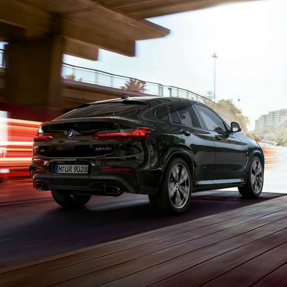 BMW X4 M40i, вид спереди с поворотом в три четверти. BMW X4 M40i в Black Sapphire металлик, за рулем, экстерьер, вид спереди с поворотом в три четверти со световыми полосками.