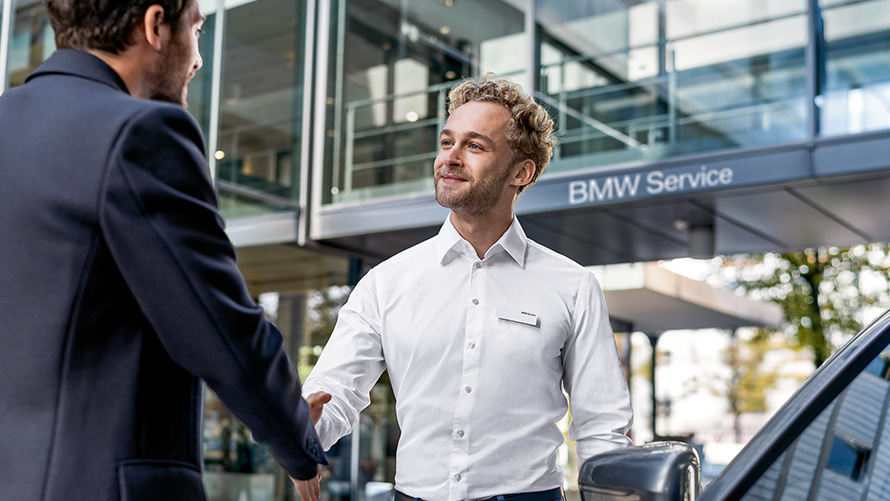 Сотрудник сервисного центра BMW приветствует клиента Сотрудник сервисного центра BMW приветствует клиента