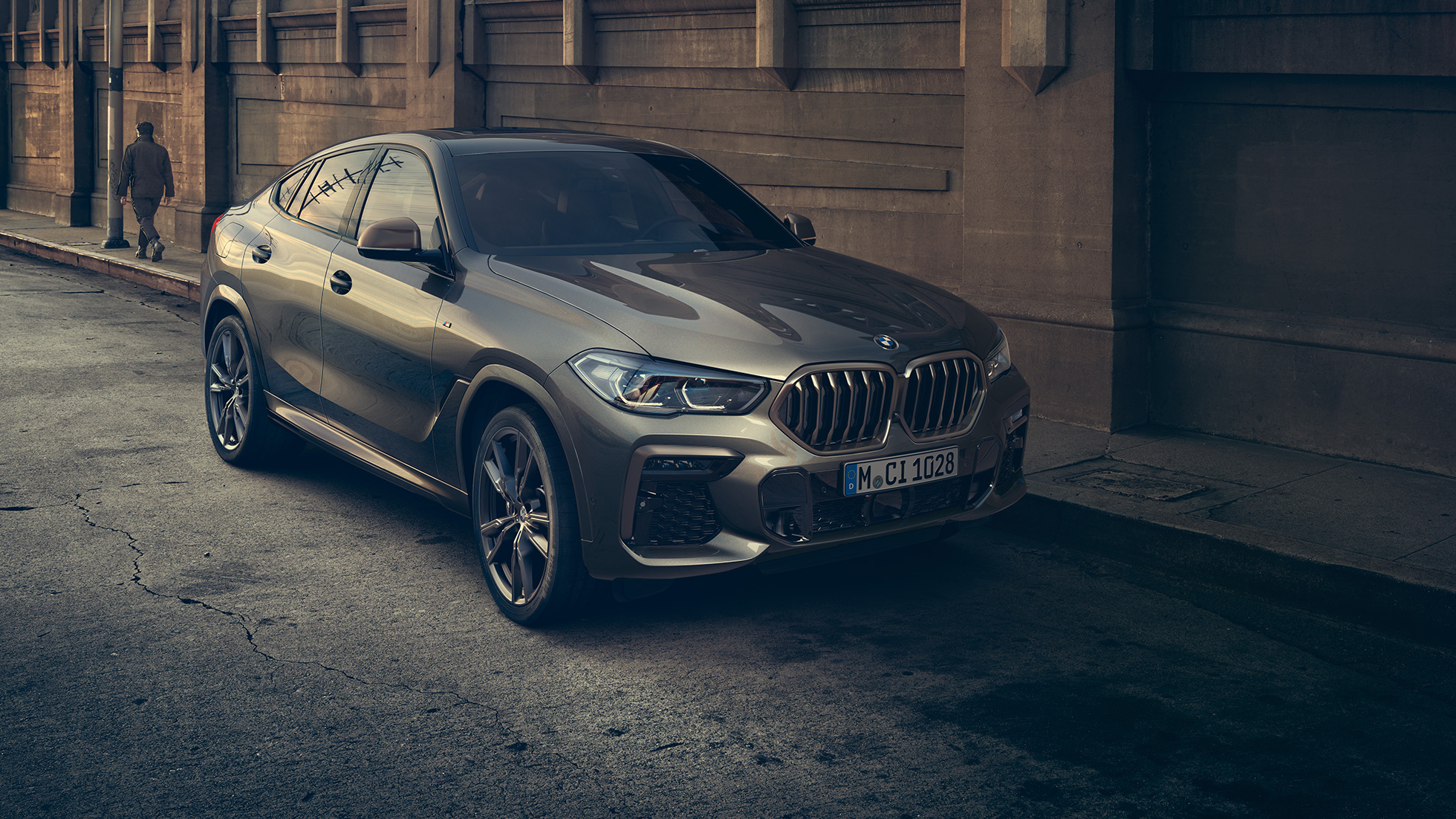 BMW X6 M50i стоит на месте. BMW X6 M50i передняя часть с поворотом в три четверти, стоящий в городской обстановке.
