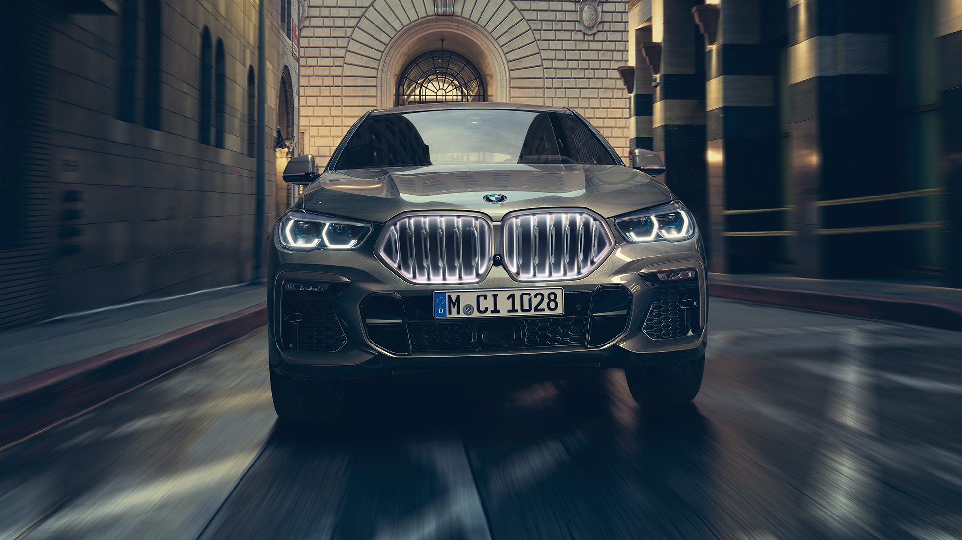BMW X6 M50i с решеткой радиатора BMW ‘Iconic Glow‘ . BMW X6 M50i в передней перспективе перед городской обстановкой.