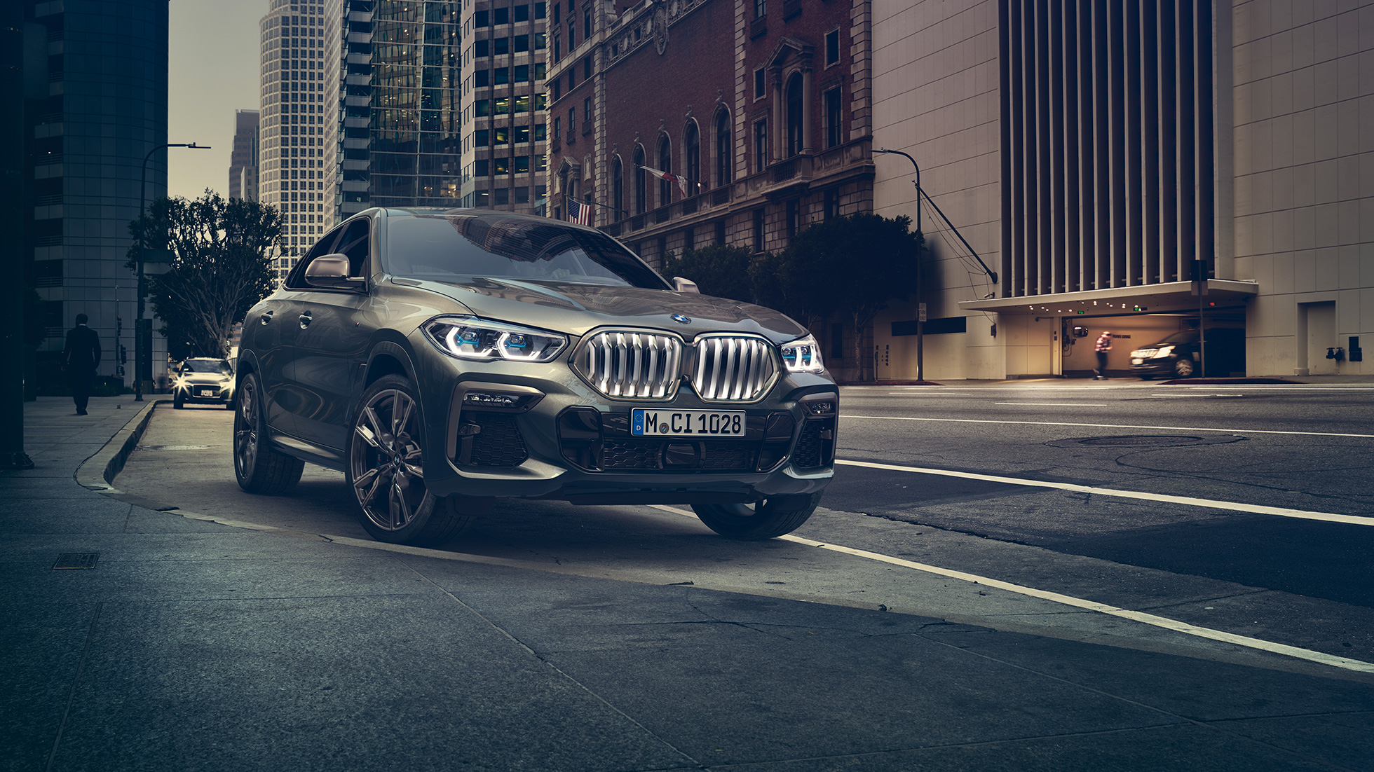 BMW X6 M50i стоит на месте. BMW X6 M50i передняя часть с поворотом в три четверти, стоящий в городской обстановке.
