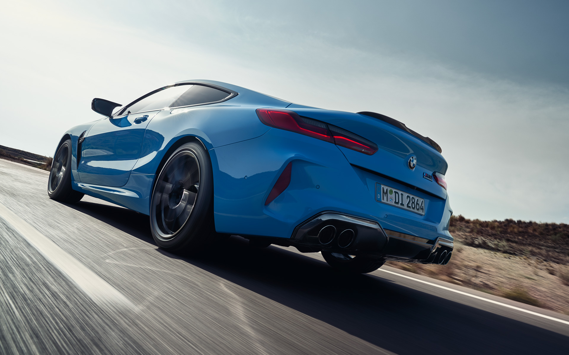 BMW M8 Competition Coupé F92 LCI (рестайлинг 2022 года) вид сзади с поворотом в три четверти, в движении BMW M8 Competition Coupé F92 LCI (рестайлинг 2022 года), Синий Дейтона-Бич, вид сзади с поворотом в три четверти, в движении на магистрали