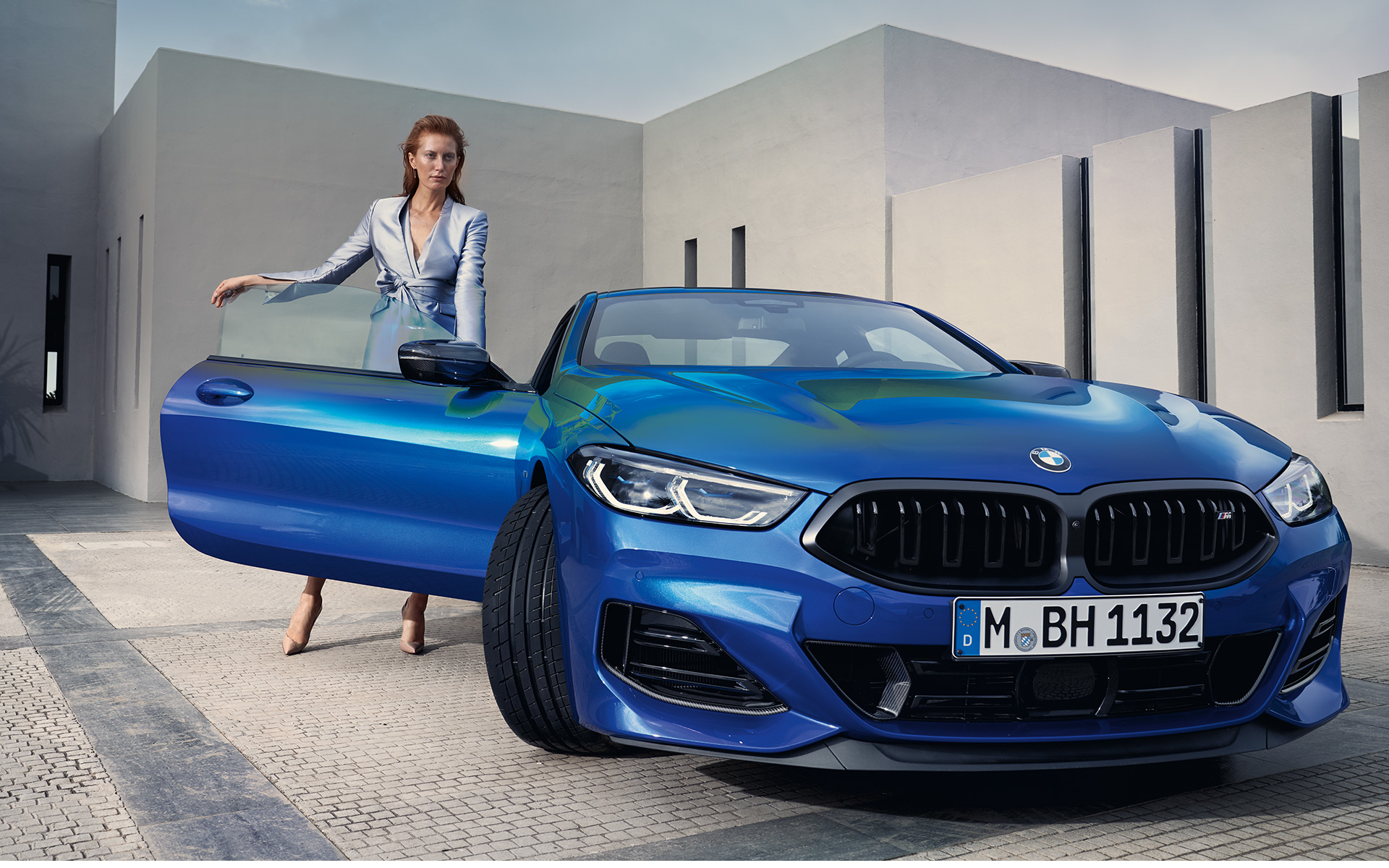 BMW M850i xDrive Coupé G15 LCI (рестайлинг 2022 года), вид спереди в статике BMW M850i xDrive Coupé G15 LCI (рестайлинг 2022 года) M Синий Портимау металлик, вид спереди в статике с женщиной перед открытой дверью