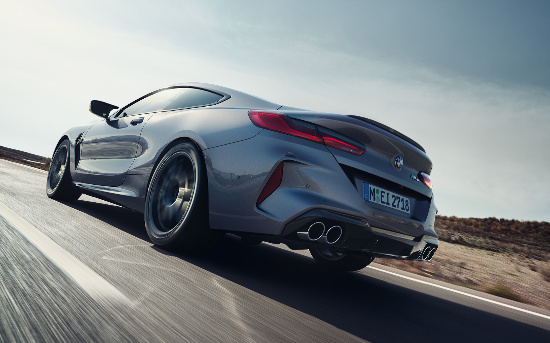 Вид сзади с поворотом в три четверти BMW M8 Coupé F92 LCI (рестайлинг 2022 года) в движении на магистрали BMW M8 Coupé F92 LCI (рестайлинг 2022 года) Серый Графит металлик, вид сзади снизу с поворотом в три четверти, в движении на магистрали