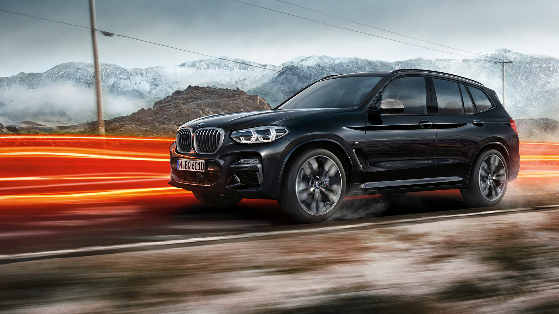 BMW X3 M40i и BMW X3 M40d, вид сбоку. BMW X3 M40i и BMW X3 M40d в Black Sapphire металлик, за рулем, экстерьер, вид сбоку перед горным пейзажем со световыми полосками.
