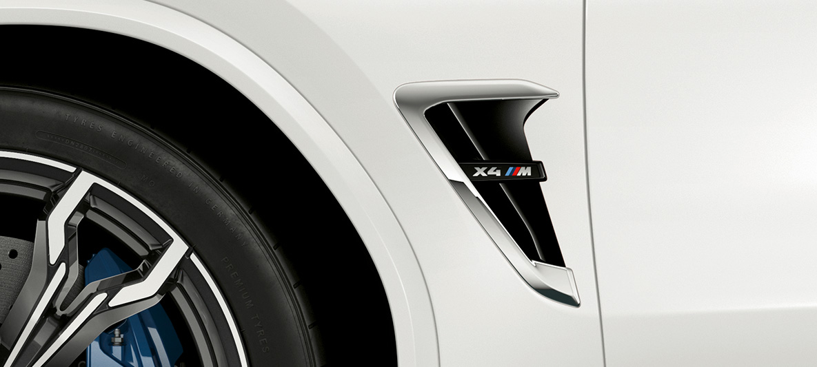 BMW X4 M, жабры M. BMW X4 M в Alpine White, экстерьер, жабры M с хромированными вставками и обозначением модели.