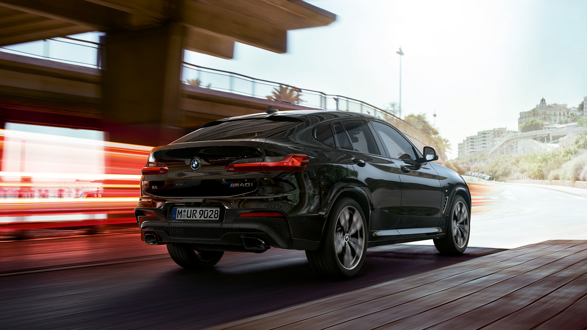 BMW X4 M40i, вид спереди с поворотом в три четверти. BMW X4 M40i в Black Sapphire металлик, за рулем, экстерьер, вид спереди с поворотом в три четверти со световыми полосками.