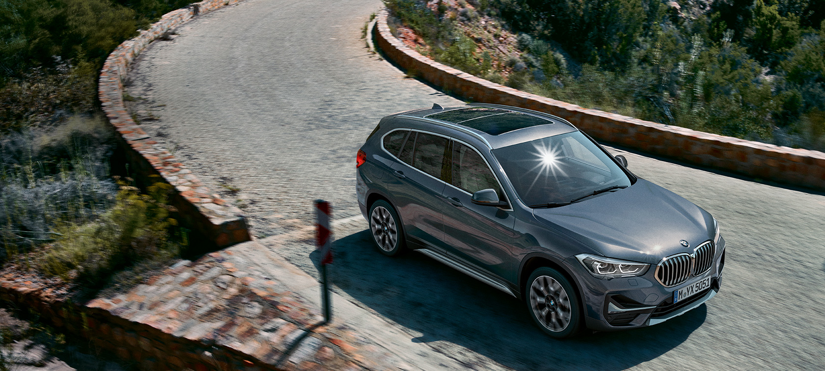 BMW X1, вид спереди с поворотом в три четверти. BMW X1, вид спереди с поворотом в три четверти на фоне горного пейзажа.