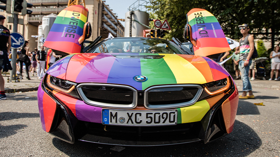 Многообразие, устойчивое развитие BMW Устойчивое развитие BMW, многообразие BMW, вид спереди на автомобиль в цветах радуги с открытой дверью типа "крыло чайки"