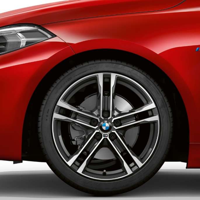 BMW 1 серии модель M Sport в Melbourne Red металлик, спереди сбоку с 17-дюймовыми легкосплавными дисками M с двойными спицами, стиль 550 M, двухцветные.